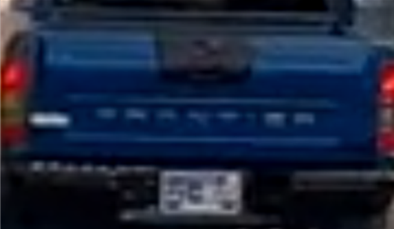 Blurry image of the back of a blue truck.