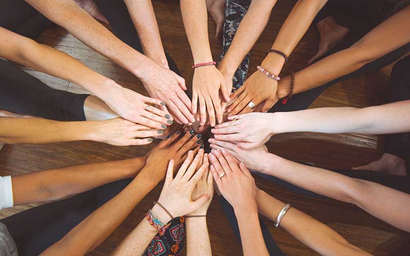 photo of womens hands overlapping in the center of a circle